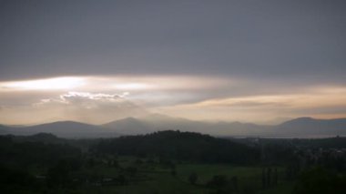 Zaman atlamalı bir küçük şehir ve dağ manzaralı bir görkemli günbatımı
