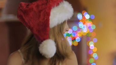 Noel Baba şapkası giyen çekici bir genç kadın saçlarını ağır çekimde twirls