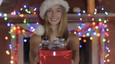 Güzel bir genç kadın sarılmış hediye Noel Baba şapkası içinde verir.