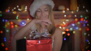 Güzel bir genç kadın Noel Noel Baba şapkası giyen geceleri hediyesi açar