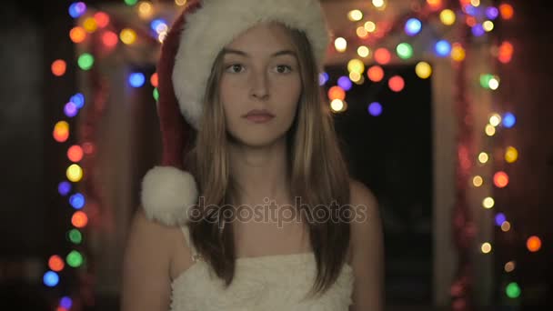 En uttråkad vacker kvinna under julen berör hår iklädd en santa hatt — Stockvideo
