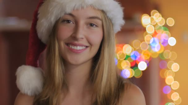 Attraktive junge Frau, die mit dem Finger einen Weihnachtsmannhut trägt — Stockvideo