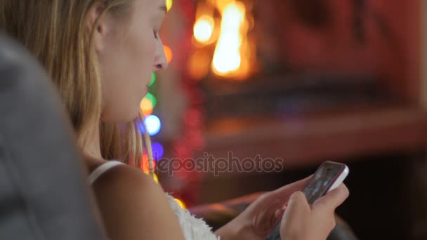 Une jeune femme blonde regarde son téléphone intelligent devant un feu 