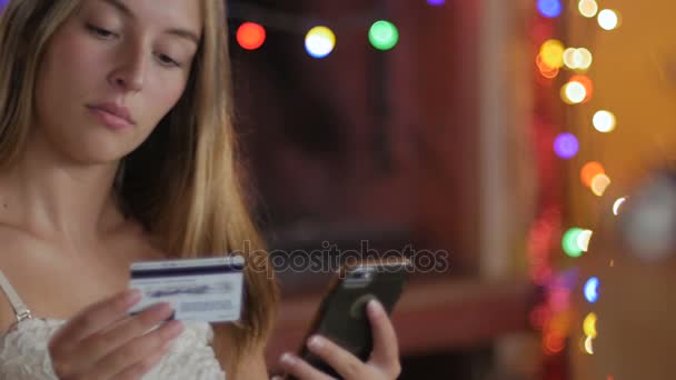 Een mooie vrouw winkels en bestellingen op haar telefoon met haar creditcard - dolly — Stockvideo