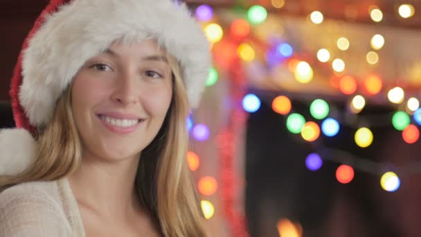 Portrait rapproché d'une femme portant un chapeau de Père Noël devant une cheminée — Video