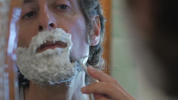 A man uses a safety razor to shave his beard - handheld — Stock Video