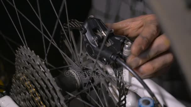 Mecánico de bicicleta haciendo ajustes a los frenos de disco de una bicicleta de montaña CU — Vídeos de Stock