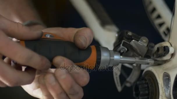 A man disassembles a rear derailleur on a bicycle with a screwdriver — Stock Video