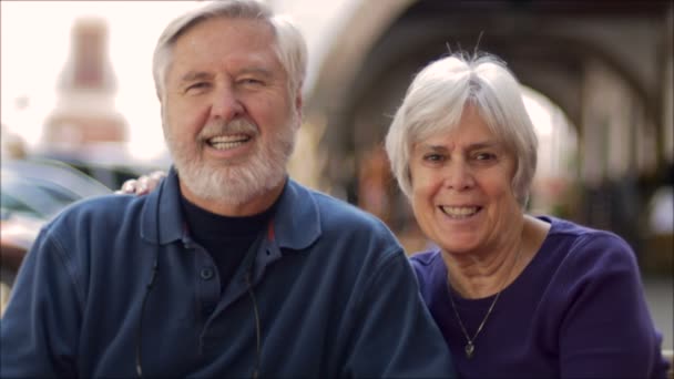 Dos ancianos jubilados sentados afuera sonríen y muestran afecto — Vídeos de Stock