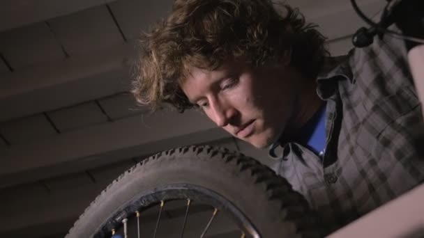 Låg vinkel av tusenåriga man cykel mekaniker arbetar på ett cykelhjul — Stockvideo