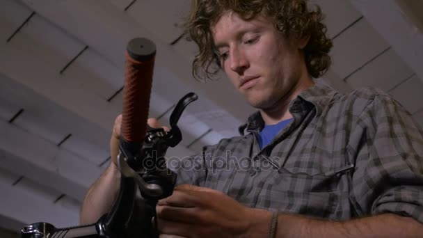 A bike mechanic attaches a cable to a gear shifter - low angle dolly — Stock Video