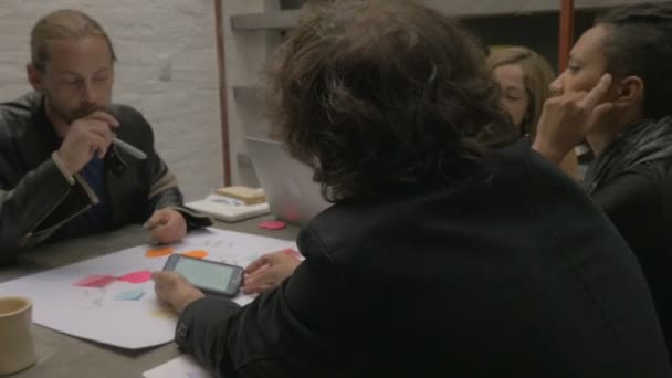 Un equipo diverso de millennials en una reunión mirando un teléfono inteligente w pantalla verde — Vídeos de Stock