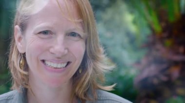 Güneş esintili - dolly atış gülümseyen güzel kızıl saçlı bir kadın