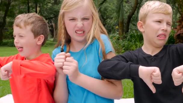 Three young children say yuck and hold their noses in disgust Stock Video