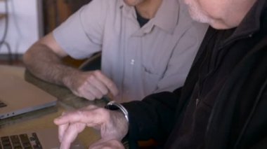 Yaşlı bir komuta sizde trackpad kullanır iken bir adam bir bilgisayara işaret eden
