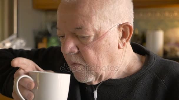 Un homme âgé buvant du café tout en portant un masque à oxygène dans slowmo — Video