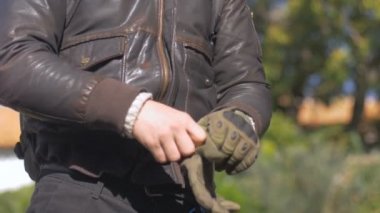 Beyaz bir adam onun çıplak elle bir motosiklet sürme eldiven koyar.