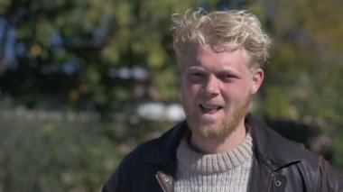 Bir yakışıklı sarışın saçlı bin yıllık sakallı adam gülümseyerek ve şaşı bir