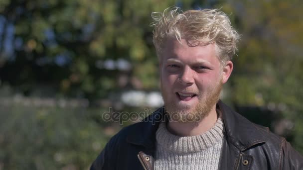 Un beau blond aux cheveux millénaires avec une barbe souriante et plissée — Video