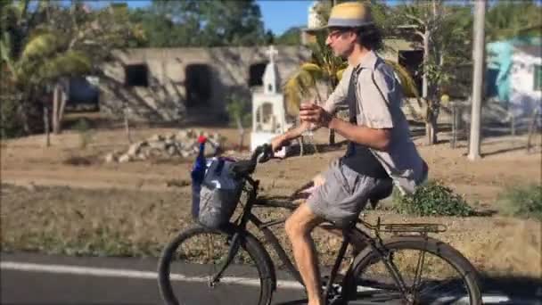Un hombre de mediana edad en bicicleta en una bicicleta de crucero de playa sosteniendo una copa de vino — Vídeo de stock