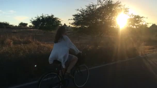 Una atractiva mujer rubia sonríe a la cámara mientras monta en bicicleta — Vídeos de Stock