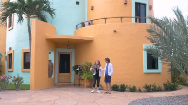 Пара стоїть перед своїм будинком, піднімаючи свого кота і посміхаючись — стокове відео