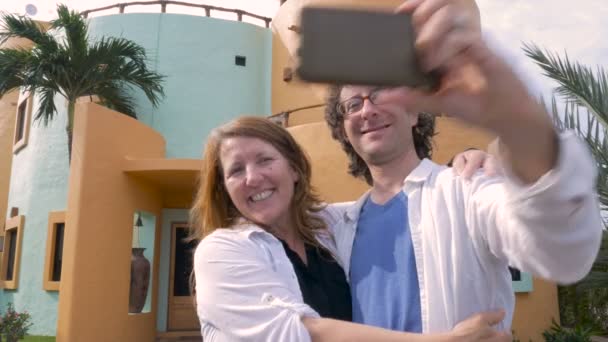 Ein Paar macht ein Selfie und betrachtet das Foto vor seinem neuen Zuhause — Stockvideo