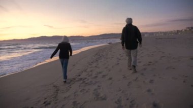 Gün batımında sahilde yürüyüş çekici bir yaşlı çift