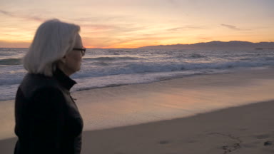 Yürüyüş ve sahilde bir gün batımı zevk olgun uygun aktif 60'lı kadın