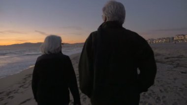 Olgun uygun etkin emekli 60'ların çift sahilde günbatımı sırasında yürüyüş