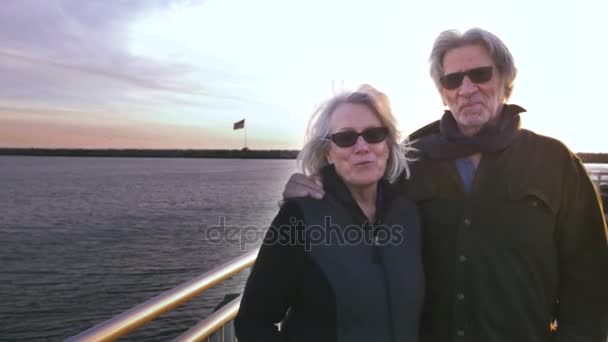 Привлекательная счастливая, улыбающаяся взрослая пара 60-х годов с флагом США на заднем плане над океаном — стоковое видео