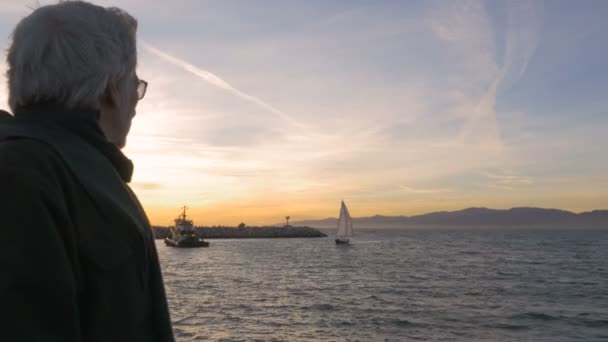 Atractivo hombre jubilado feliz disfrutando de la puesta de sol con velero en el océano — Vídeos de Stock