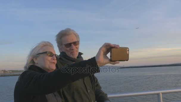 Attraktiva äldre par i 60-årsåldern ta selfie på ocean med smartphone vid solnedgången — Stockvideo