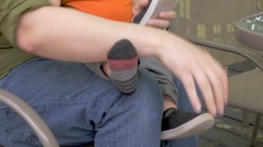 Genç bir baba, yürümeye başlayan çocuk oğlunun ayakkabılarınızı alır ve kendi ayakları gıdıklıyor