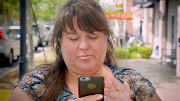 Une belle femme pleine figuré en utilisant sa technologie de téléphone intelligent sur le trottoir de la ville — Video