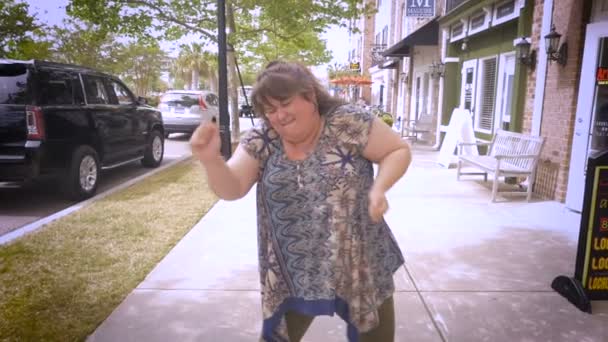 Eine lustige Frau tanzt und pumpt ihre Arme in die Luft auf einem Bürgersteig der Stadt — Stockvideo