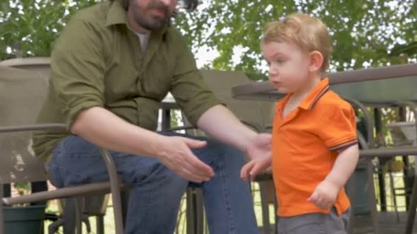 Un padre vigile siede accanto al suo bambino accanto a lui — Video Stock