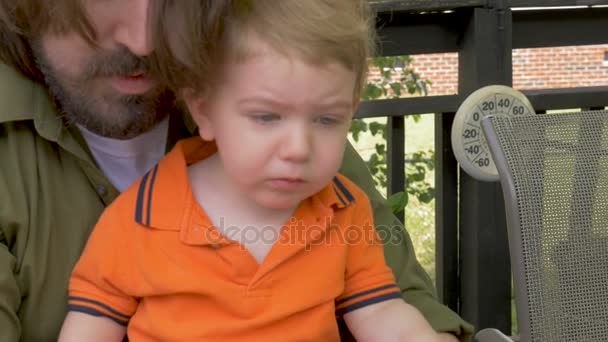 Een vader schoenen van de jongen van zijn jonge moe kind zetten en dan klappen — Stockvideo