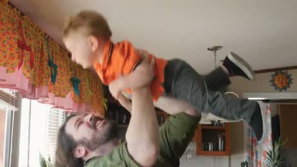 Залишайтеся вдома тато піднімає свого хлопчика в повітрі і цілує його вдома — стокове відео