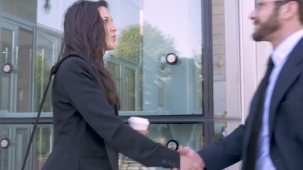 Дві привабливі молоді бізнесмени тремтять руками за межами офісної будівлі — стокове відео