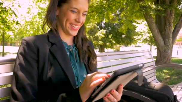 Счастливая улыбающаяся деловая женщина, работающая над цифровой планшетной технологией в парке — стоковое видео