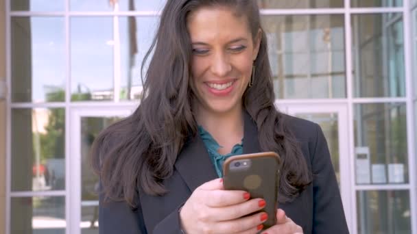 O frumoasă femeie de afaceri fericită care se uită în sus și zâmbește de la telefonul ei inteligent — Videoclip de stoc