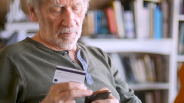 Anciano ingresando números de tarjeta de crédito en su teléfono inteligente para su compra — Vídeos de Stock