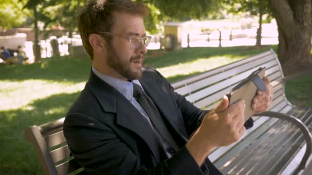 Atraktivní 30s muž hrát videohry na digitální dotykový tablet mimo — Stock video