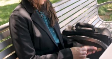 Akıllı telefonuna cevap bir parkta bankta bir bilgisayarda çalışan kadın