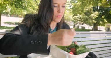 Genç kadın bir besleyici sağlıklı karışık yeşil salata ile çilek yemek