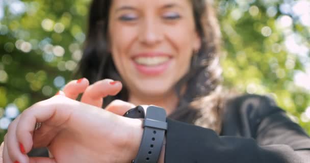 Låg vinkel på nära håll av en leende glad kvinna med en smart klocka utanför -4 k — Stockvideo