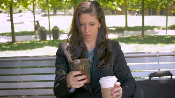 Hermosa mujer leyendo la tecnología de la aplicación del teléfono móvil en el banco del parque — Vídeos de Stock