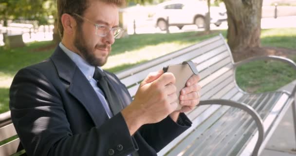 Man tar en paus från arbetet som spelar spel på sin surfplatta utanför — Stockvideo