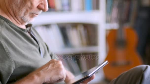 Красивый зрелый мужчина пожилого возраста, использующий цифровой планшет онлайн в своем доме — стоковое видео